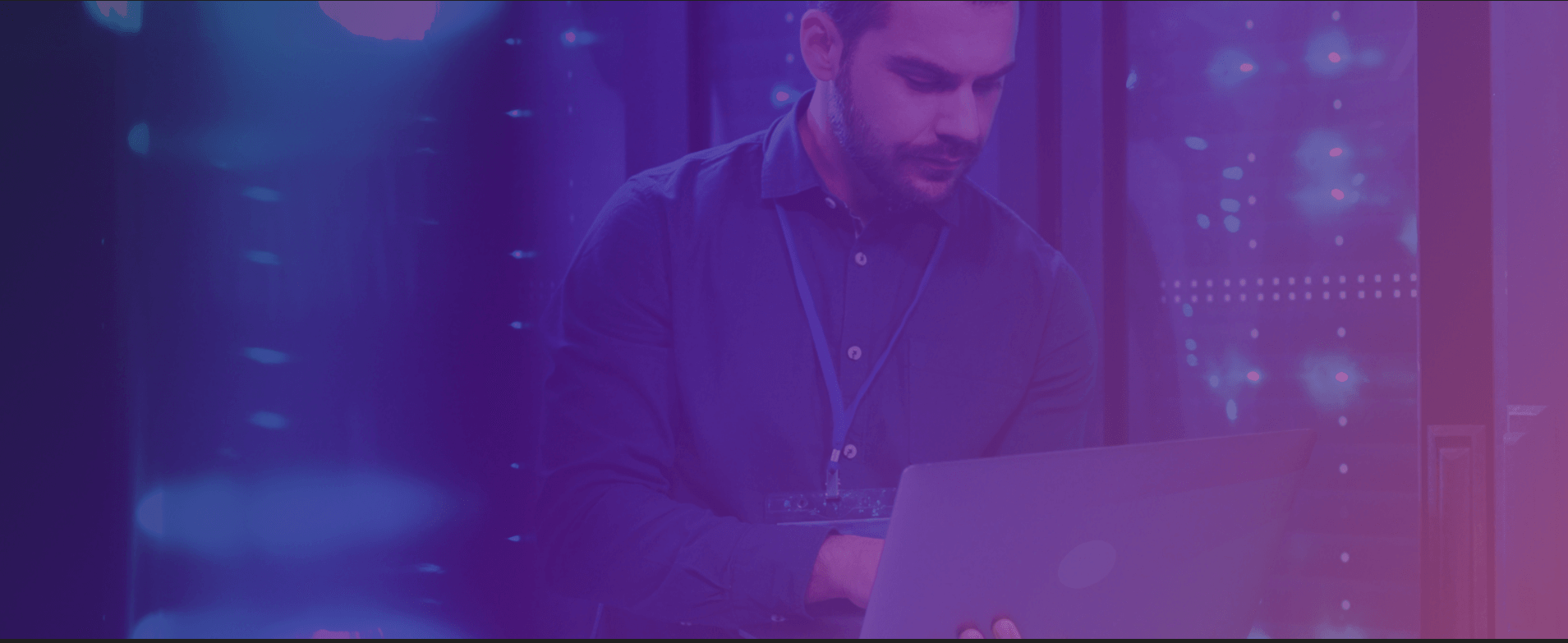 Man in a server room holding laptop resolving server issues
