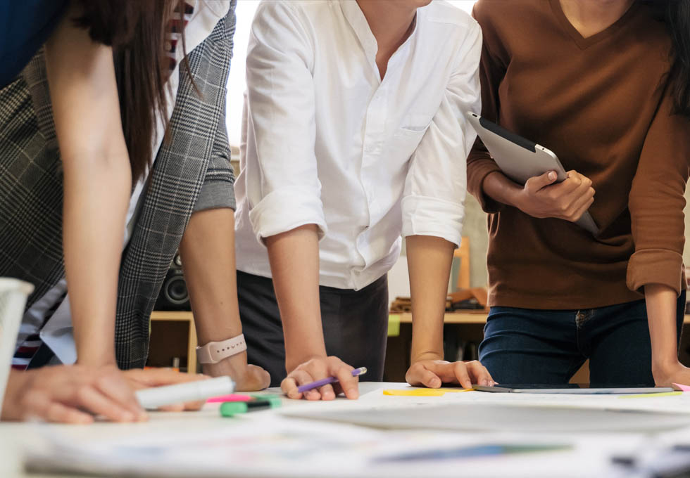 people stood over desk discussing work