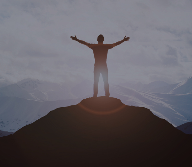 Man on top of a hill with arms stretched out